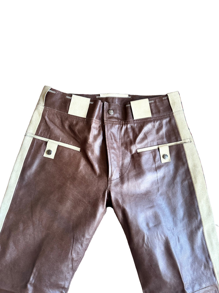 Brown leather pants with white suspenders on a patterned rug